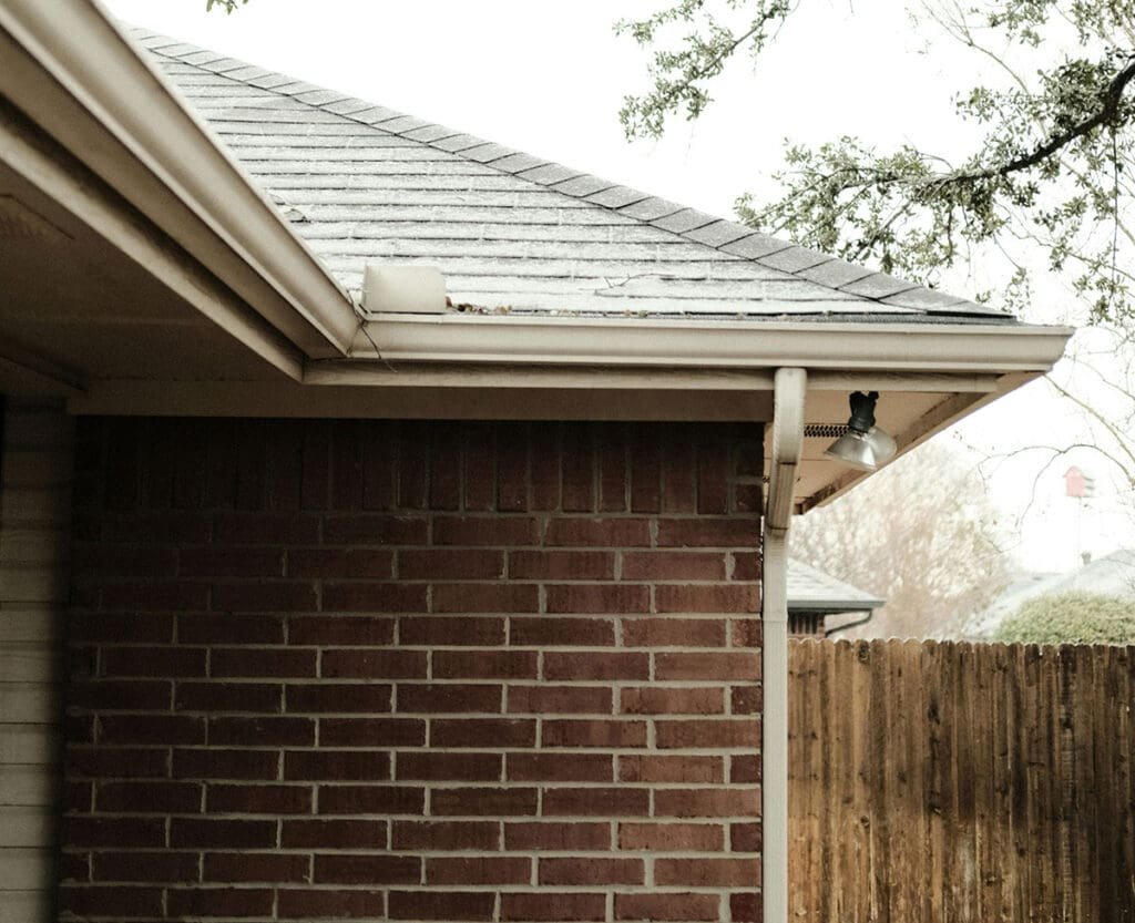 Cleaning gutters and clearing downspouts to prevent winter overflow and ice at entries