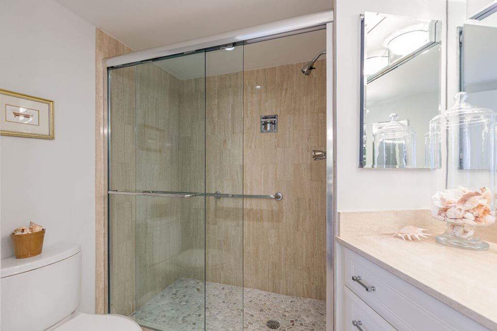 Walk-in shower with clear glass door beside a shower curtain to illustrate doors vs. curtains in a remodeled bathroom