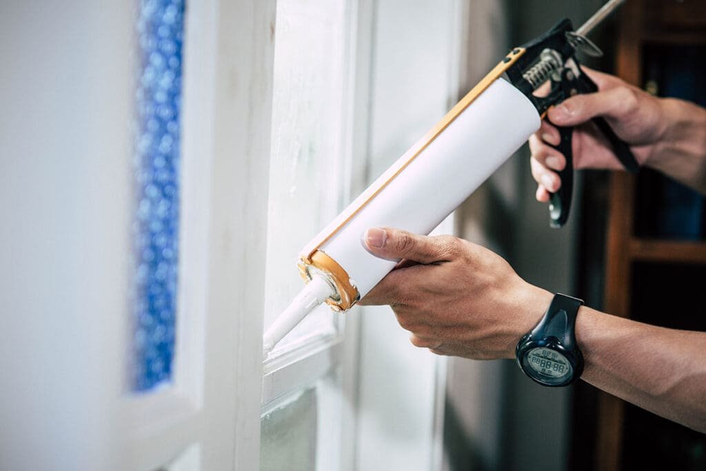 Sealing interior window trim with paintable caulk to winterize your house in Terre Haute